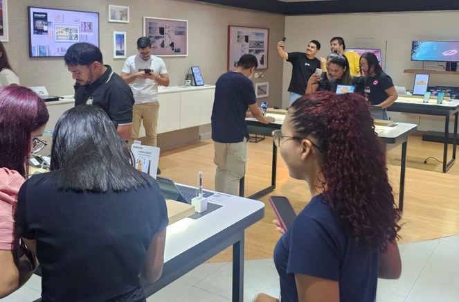 Foto mostra grupo de pessoas olhando exposição de equipamentos eletrônicos