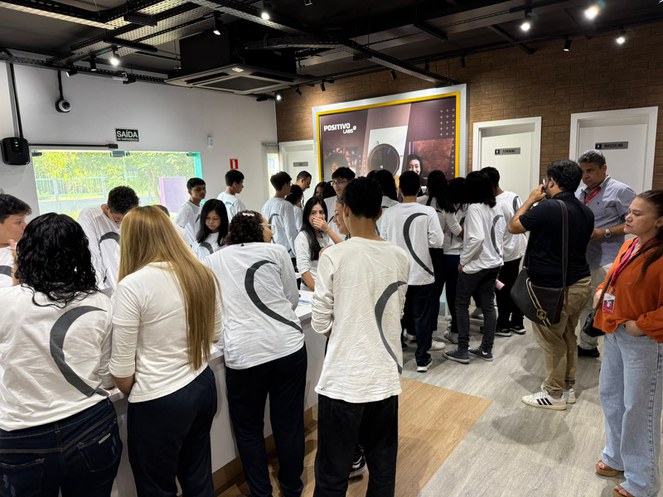 Foto mostra grupo de alunos de blusa branca em um laboratório