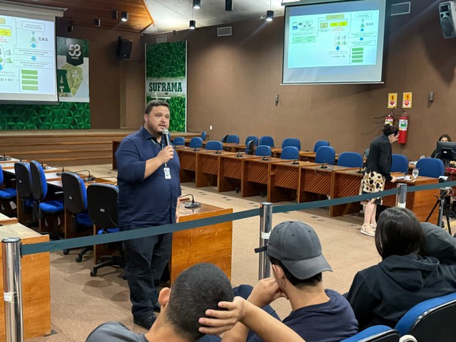 Foto mostra homem de blusa azul falando com microfone na mão