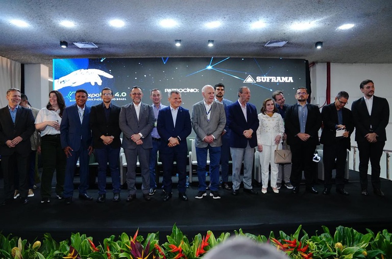 Foto mostra grupo de pessoas em pé num evento