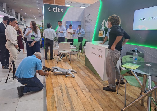 Foto mostra homem filmando o movimento de um pequeno robô em uma feira de tecnologia