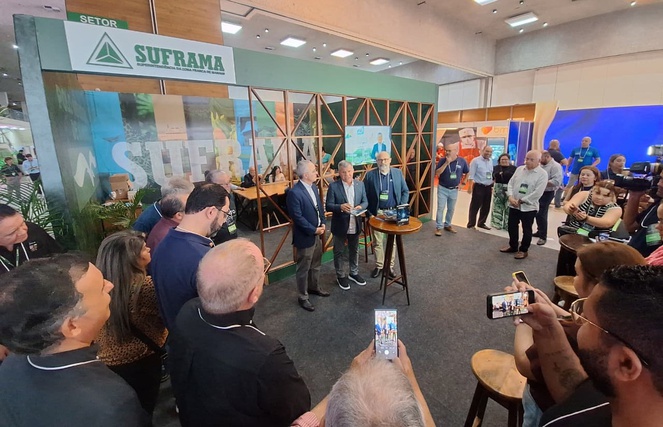 Foto mostra homem falando com livro na mão, observado por grupo de pessoas