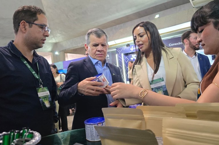 Foto mostra mulher apresentando produto a um homem de blazer azul em uma feira de inovação