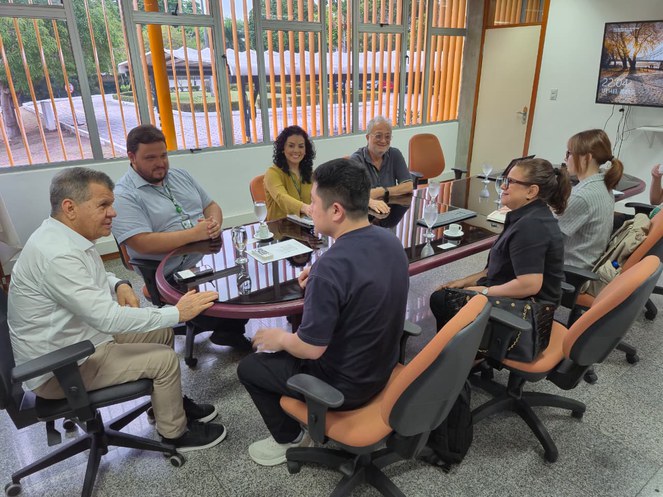 Foto mostra pessoas em reunião num ambiente fechado