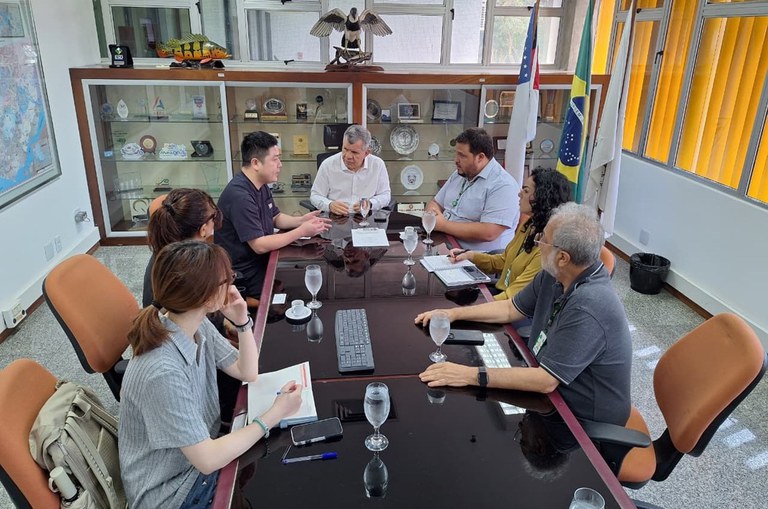 Foto mostra pessoas em reunião sentados à mesa