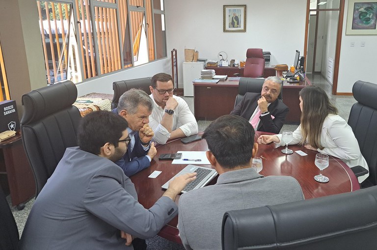 Pessoas reunidas ao redor de uma mesa redonda olhando para um computador