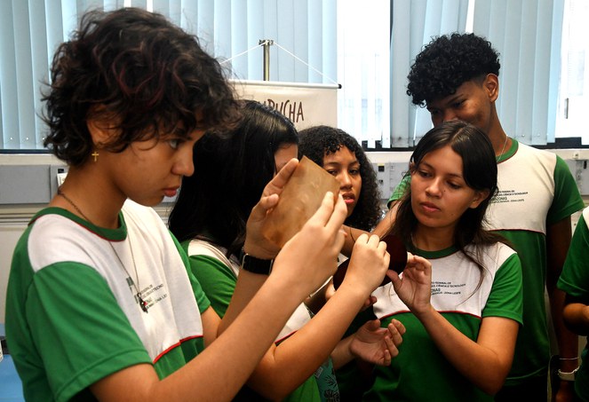 Foto mostra jovem olhando para um objeto