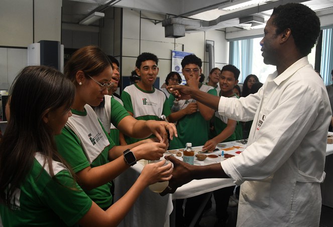 Foto mostra homem de jaleco branco mostrando objeto