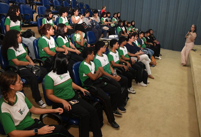 Foto mostra mulher em pé com microfone na mão