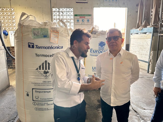 Dois homens conversam em um galpão industrial