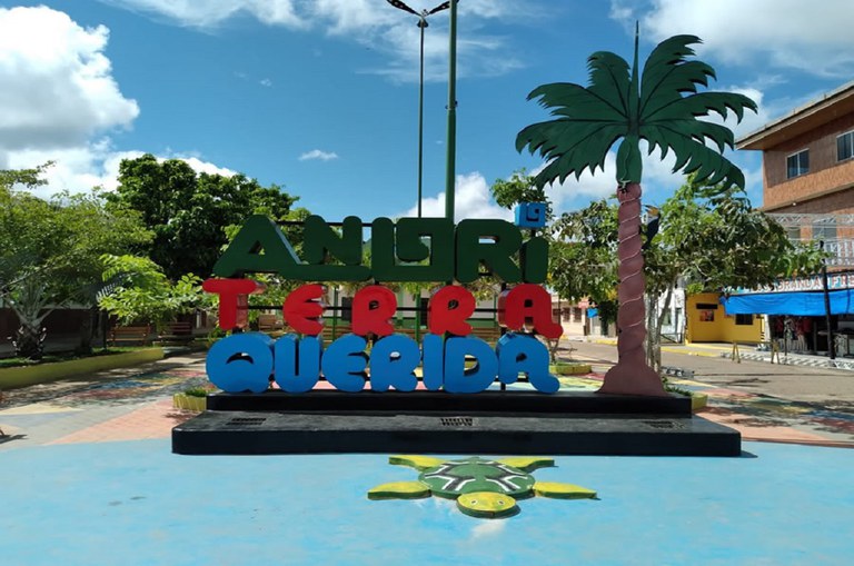 Foto mostra frente de uma cidade com uma placa dizendo: Anori terra querida