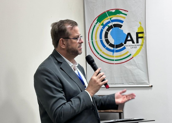 Foto mostra homem de blazer falando ao microfone