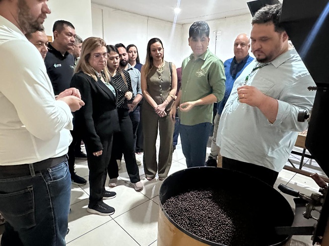 Foto mostra pessoas olhando para uma saca de café