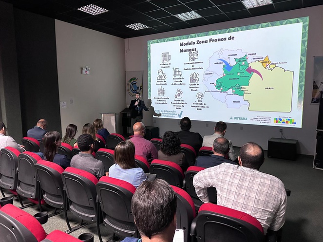 Foto mostra homem de blazer fazendo uma apresentação com telão ao fundo