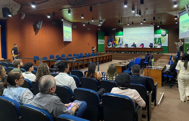 Foto mostra auditório grande com pessoas num evento