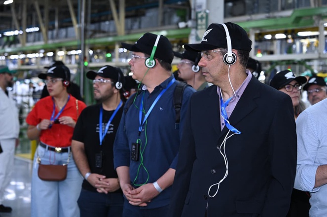 Foto mostra um grupo de pessoas visitando uma fábrica de motocicletas