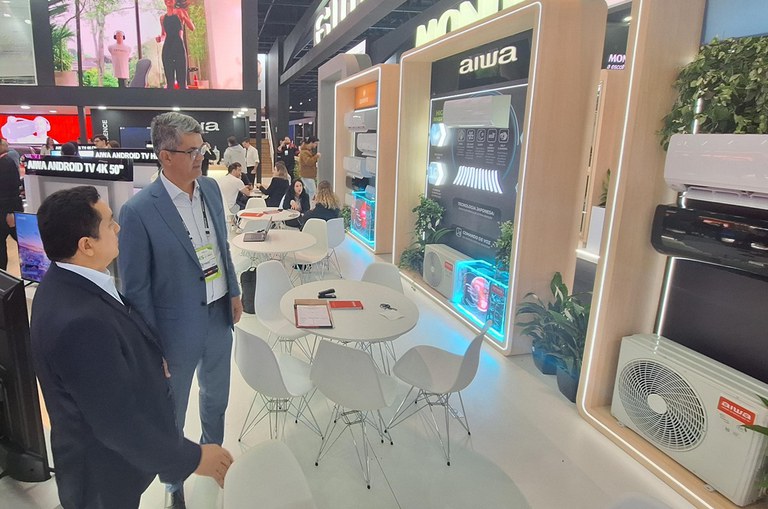 Foto mostra homens olhando para condicionadores de ar em exposição