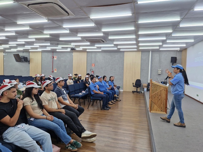Foto mostra mulher em pé falando a grupo de pessoas