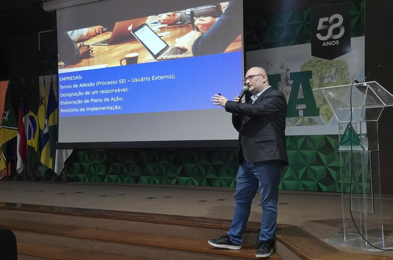 Foto mostra homem de blazer e microfone na mão