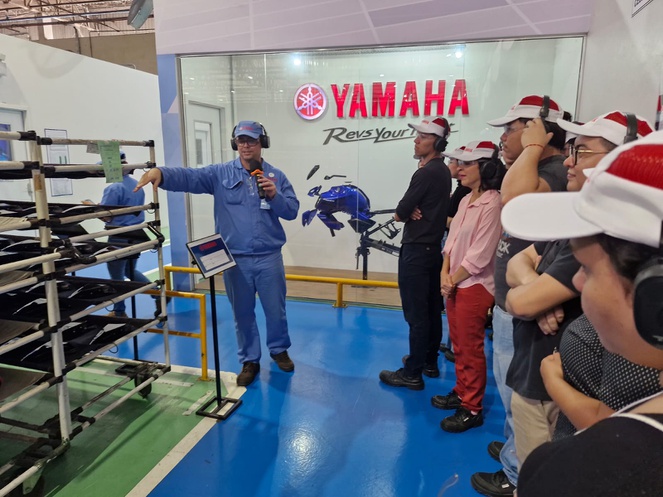 Foto mostra homem mostrando peças de motocicletas a grupo de estudantes