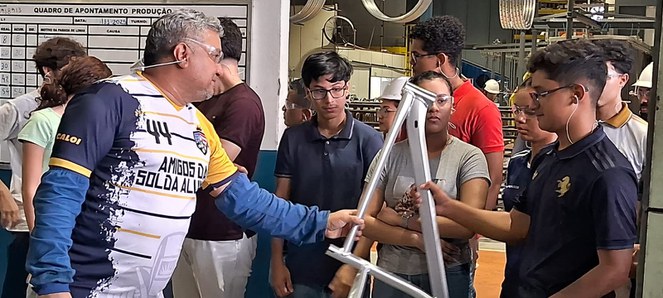 Foto mostra homem entregando peça de bicicleta a jovem