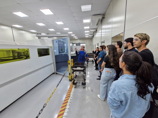 Foto mostra homem de jaqueta azul e óculos escuros falando a um grupo de pessoas