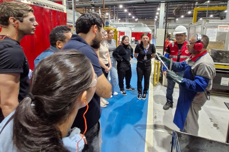 Foto mostra homem mostrando uma peça de bicicleta a grupo de pessoas