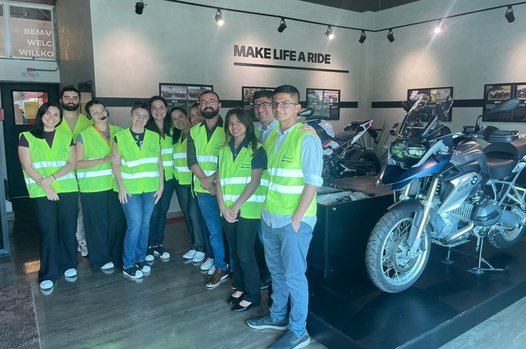 Foto mostra grupo de pessoas posando para fotografia ao lado de motocicletas