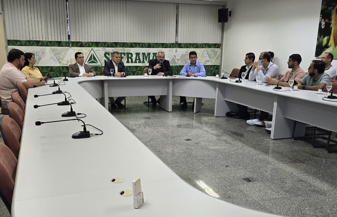Foto mostra homem fazendo uma explanação numa reunião a um grupo de pessoas