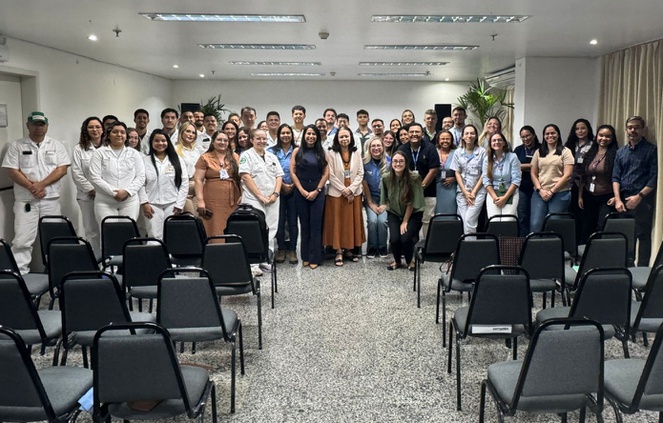 Foto mostra grupo de pessoas em pé, posando para uma sessão de fotos