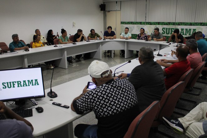 Grupo de pessoas reunidos em uma sala com uma grande mesa oval