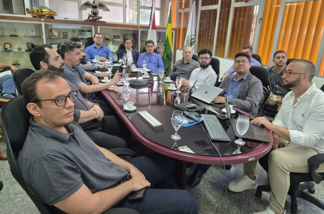 Foto mostra algumas pessoas em reunião numa sala fechada