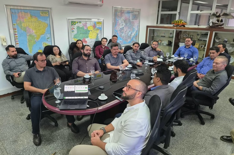 Foto mostra pessoas em reunião numa sala fechada