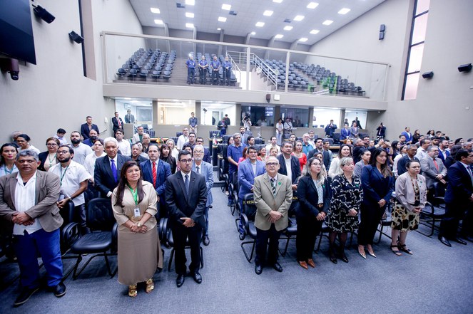 Foto mostra grupo de pessoas cantando o Hino Nacional