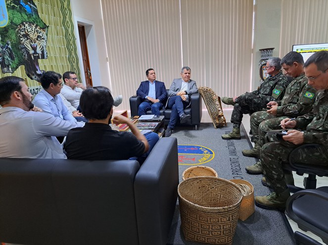 Foto mostra um grupo de homens formados com farda do Exército em reunião com civis