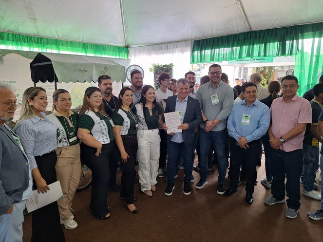 Foto mostra homem segurando um documento ao lado de outras pessoas