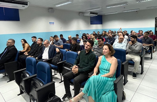 Foto mostra pessoas sentadas num auditório