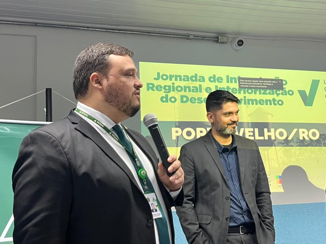 Foto mostra homem de blazer falando ao microfone