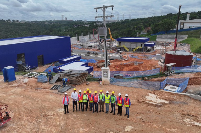 Foto mostra grupo de homens com equipamentos de proteção em um grande empreendimento