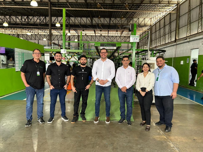 Pessoas em pé posando para uma foto dentro de uma fábrica