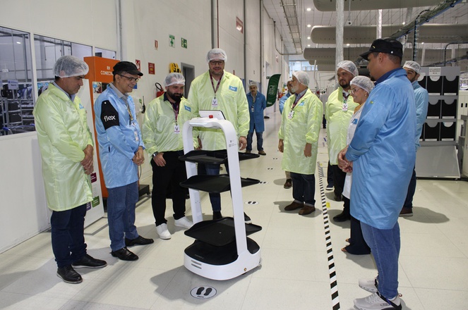 Foto mostra umas pessoas de jaleco e boné olhando para equipamentos eletrônicos