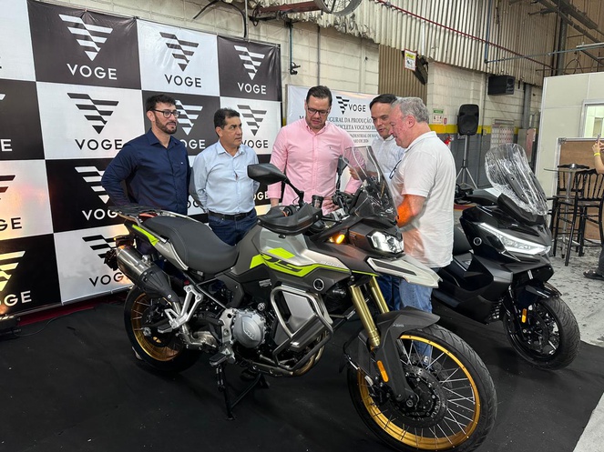 Foto mostra grupo de pessoas observando uma motocicleta