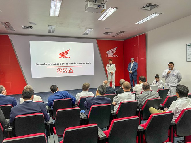 Foto mostra homem de branco falando ao microfone a um grupo de pessoas