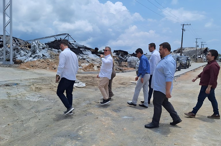 Foto mostra grupo de pessoas andando, com destroços de um prédio ao fundo, após incêndio