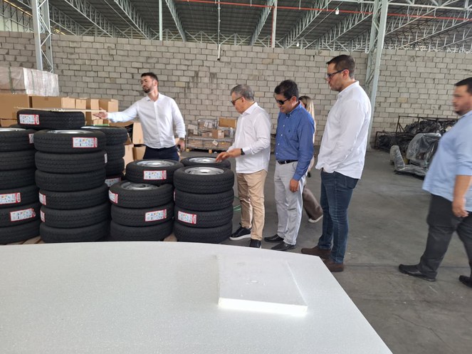 Foto mostra grupo de pessoas olhando e mexendo em pneus