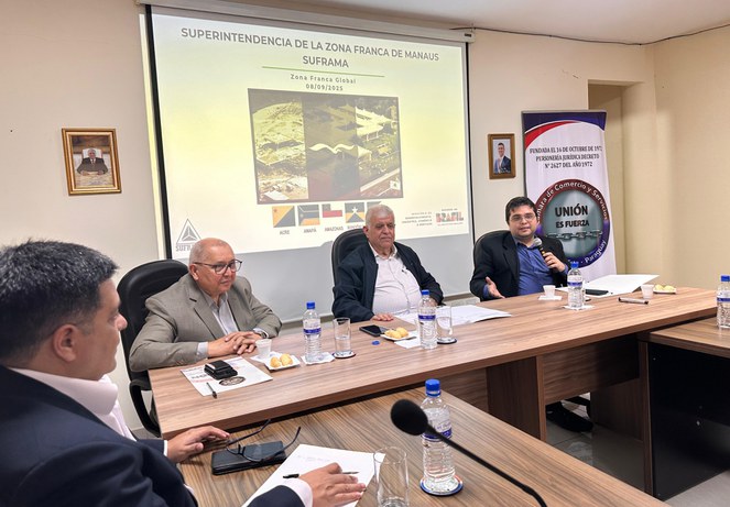 Foto mostra homem falando ao microfone e um painel ao fundo