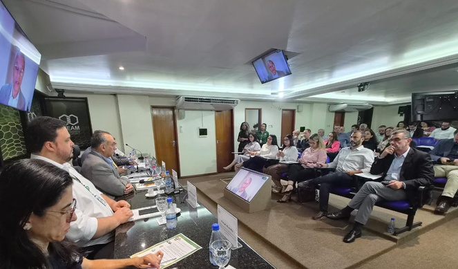 Fotom mostra pessoas sentadas numa reunião em um auditório