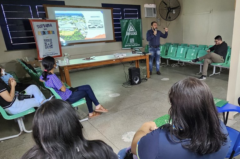Foto mostra homem de azul com microfone na mão durante explanação