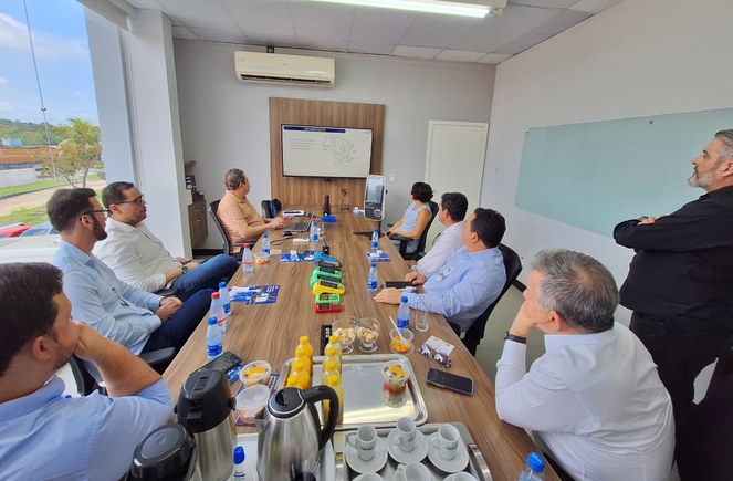 Foto mostra homem fazendo uma explanação, com o apoio de um telão