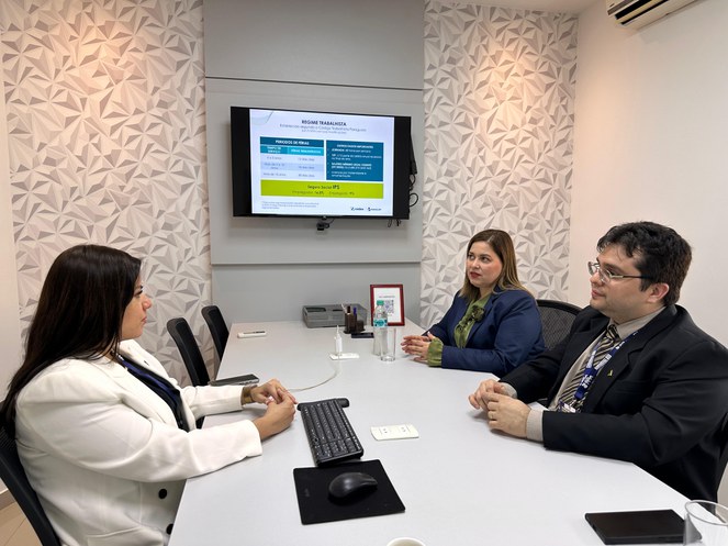 Foto mostra três pessoas em uma reunião